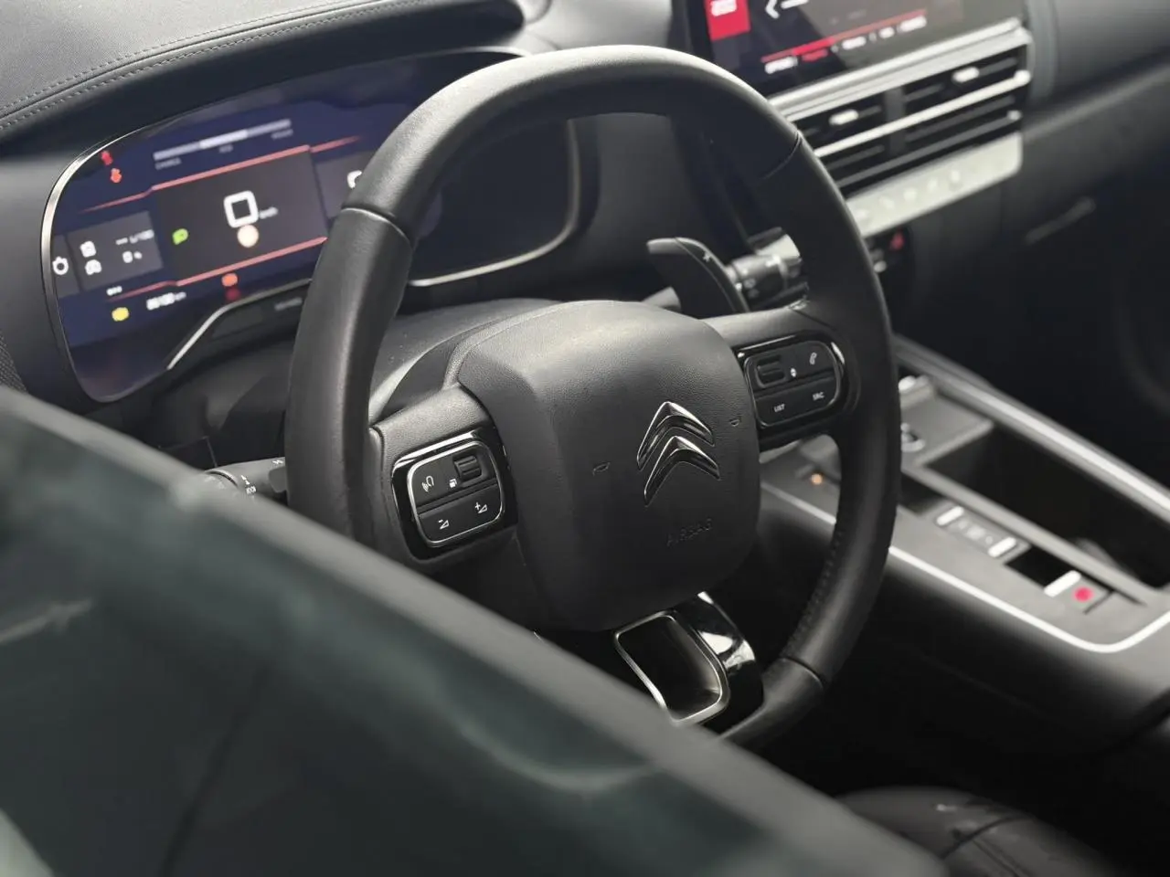 Vue intérieure centrée sur le volant cuir noir et le combiné numérique du Citroën C5 Aircross Hybrid 2024.