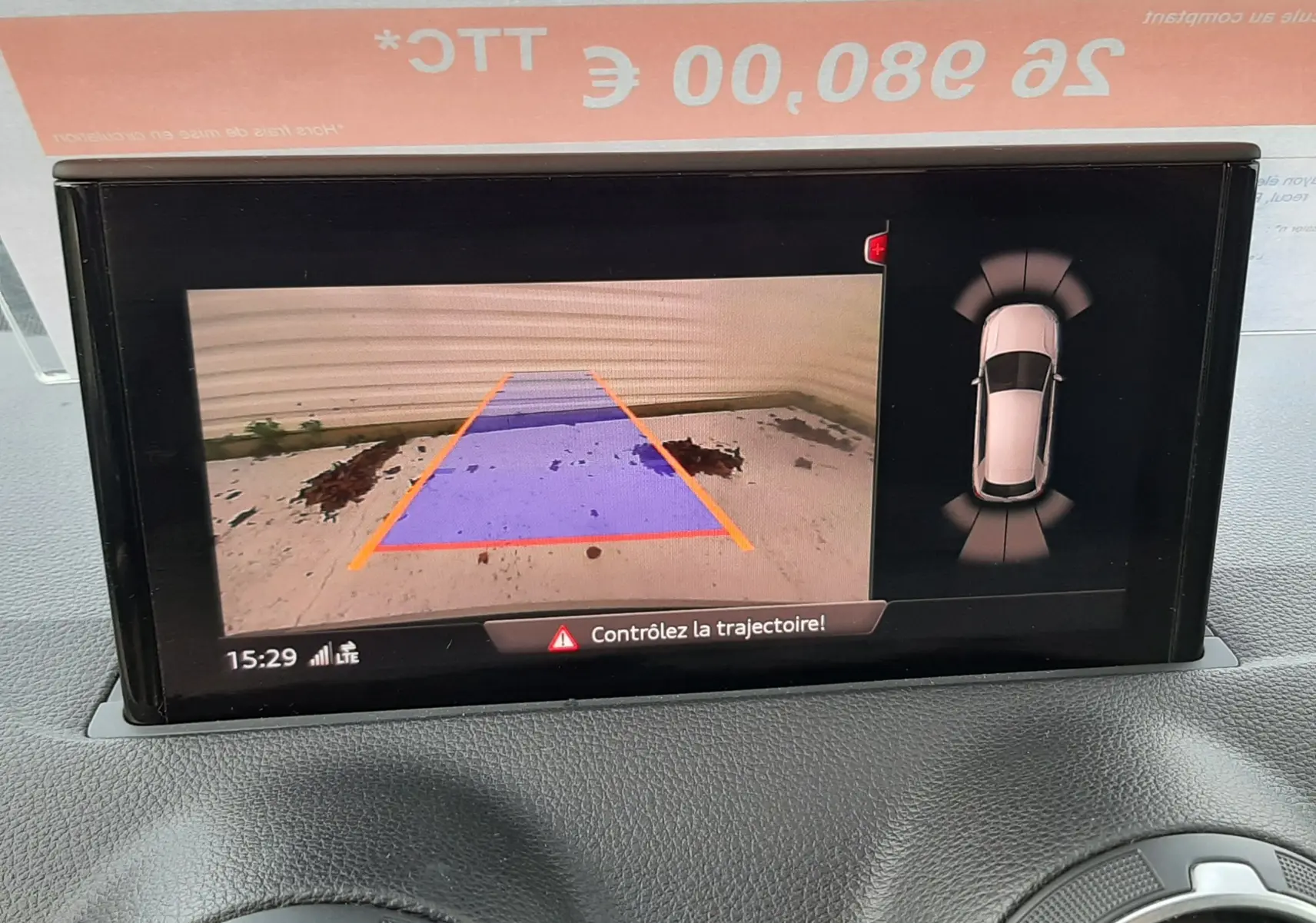 Écran multimédia montrant la caméra de recul et l'aide au stationnement d'un Audi Q2 noir mito metal, intérieur avant.