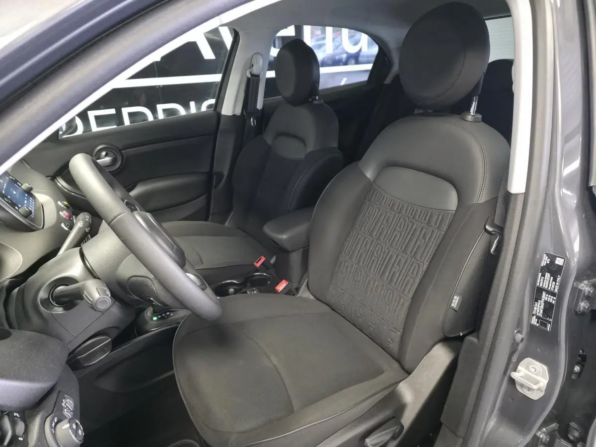 Vue intérieure côté conducteur du Fiat 500X gris, mettant en valeur les sièges en tissu noir avec monogramme Fiat.