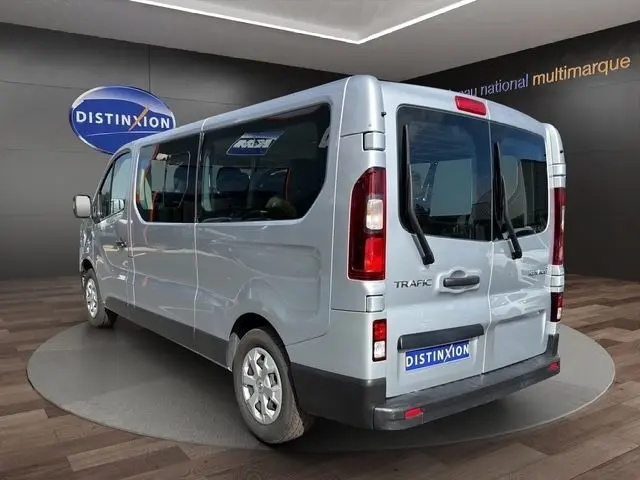 Vue 3/4 arrière droite d’un Renault Trafic Fourgon gris clair avec vitres latérales et portes arrière vitrées.