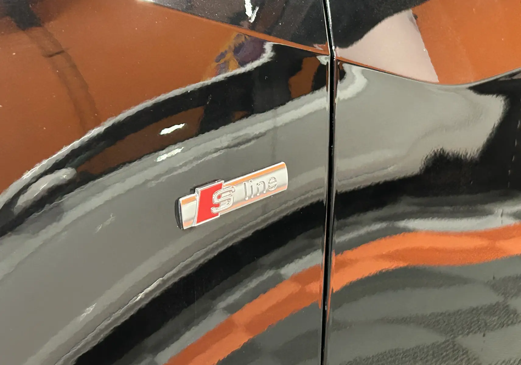 Poignée de porte noire métallisée en gros plan sur une Audi Q2 35 TFSI 2023, reflet du véhicule visible.