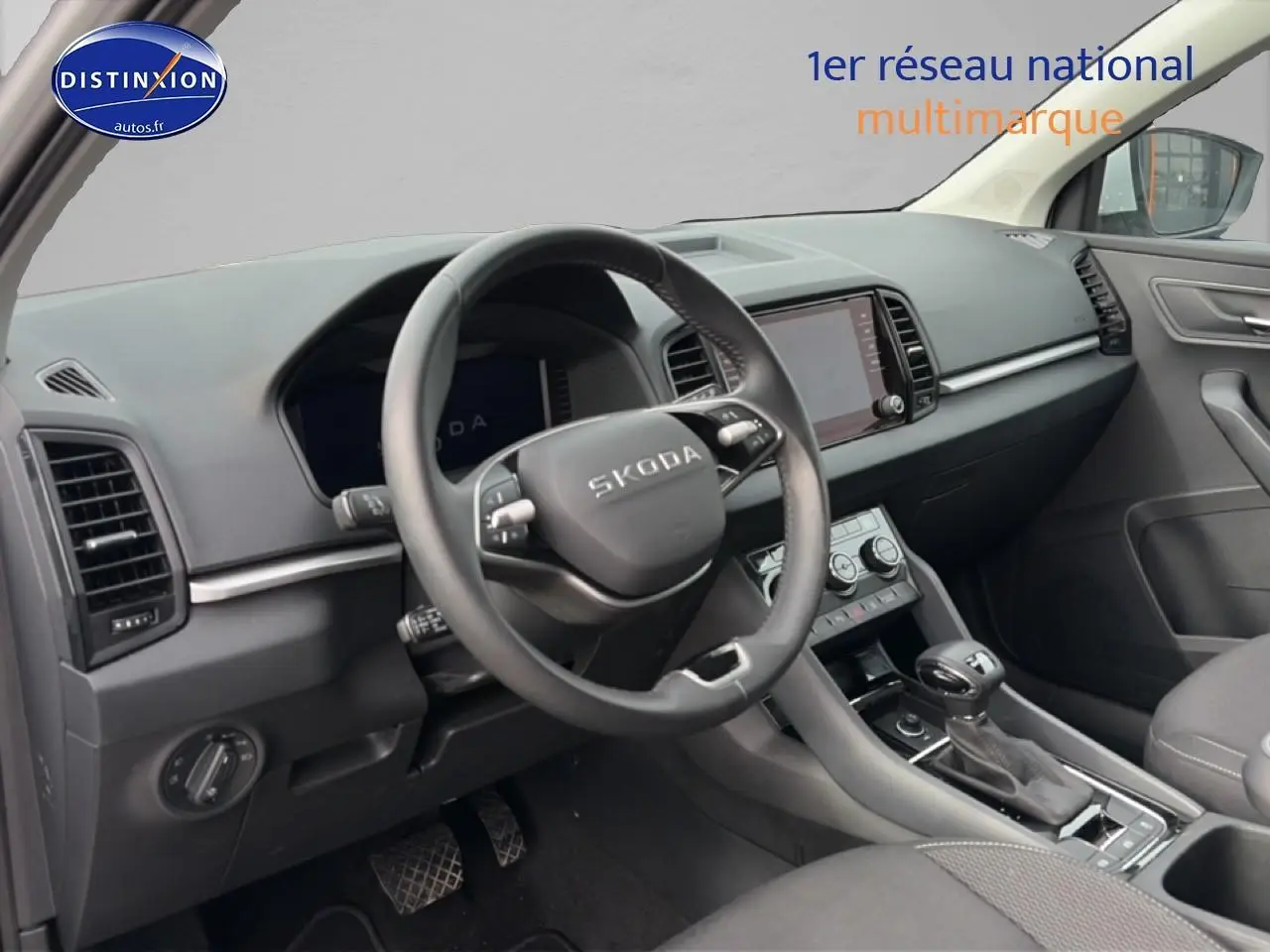 Vue intérieure côté conducteur du tableau de bord et volant cuir noir du Skoda Karoq blanc glacial 2025 avec écran tactile central.