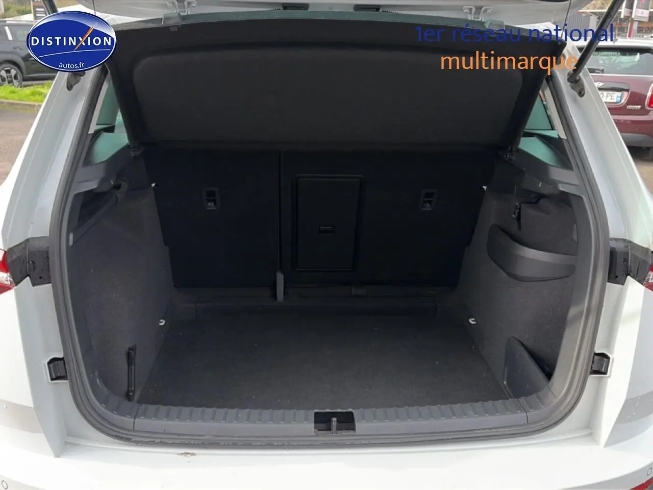 Coffre ouvert vu de l'arrière d'un Skoda Karoq blanc glacial, montrant un espace de rangement spacieux et noir.