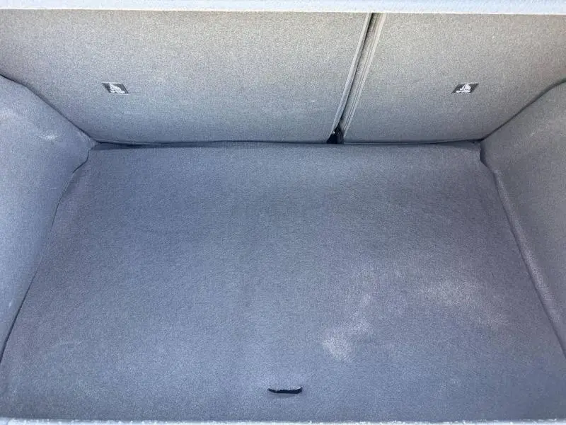 Vue intérieure du coffre vide de la Peugeot 208 1.2 100ch Allure, revêtement gris uniforme sans objets visibles.