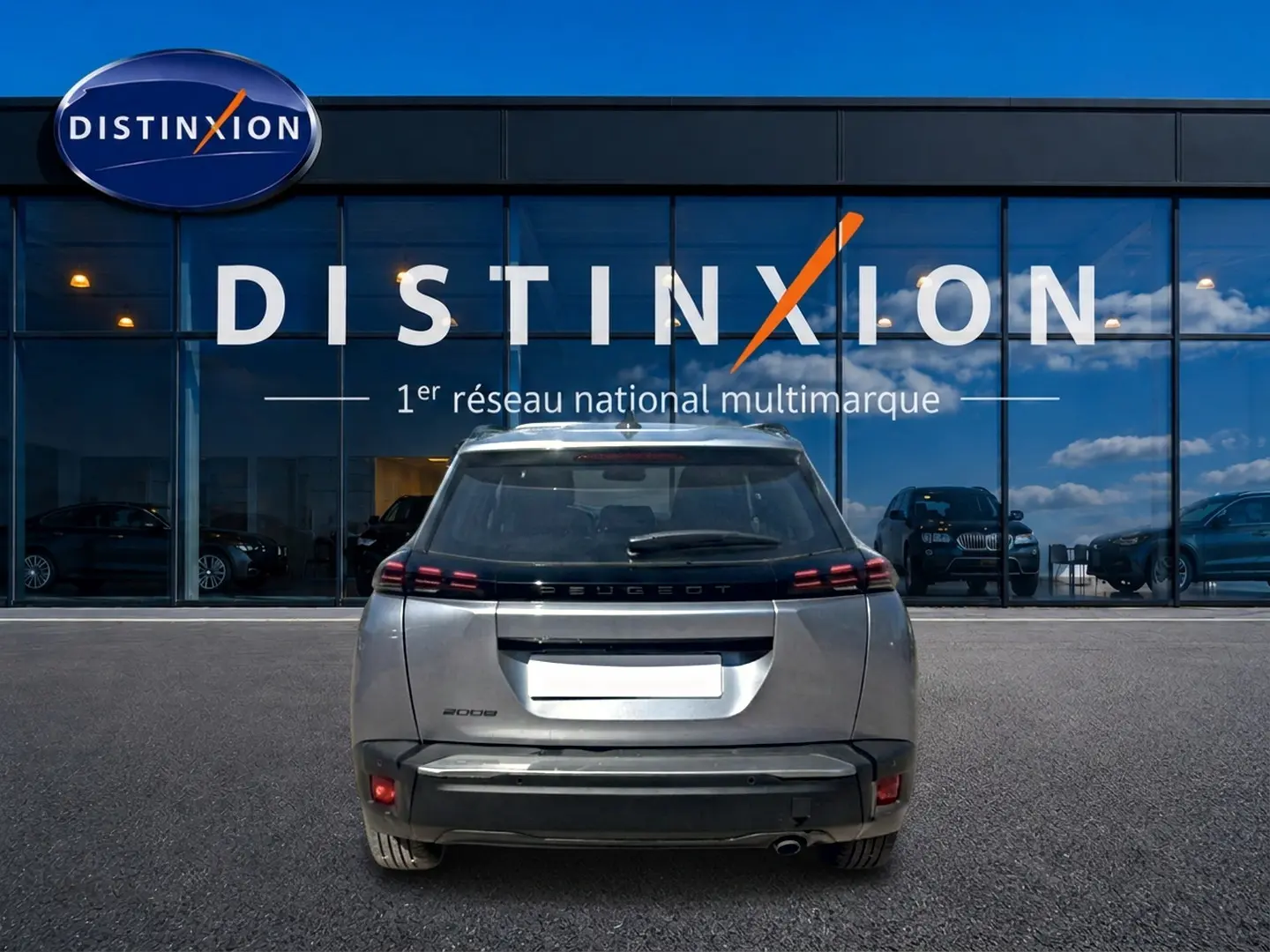 Vue arrière d'un Peugeot 2008 gris artense garé devant une vitrine avec logo Distinxion en arrière-plan.