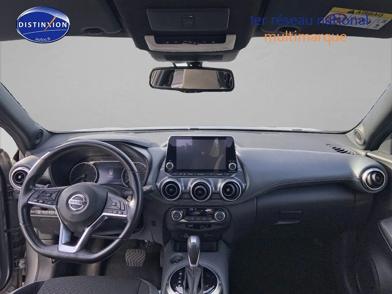 Intérieur noir du Nissan Juke 2021, vue frontale du tableau de bord avec écran tactile et volant multifonction.