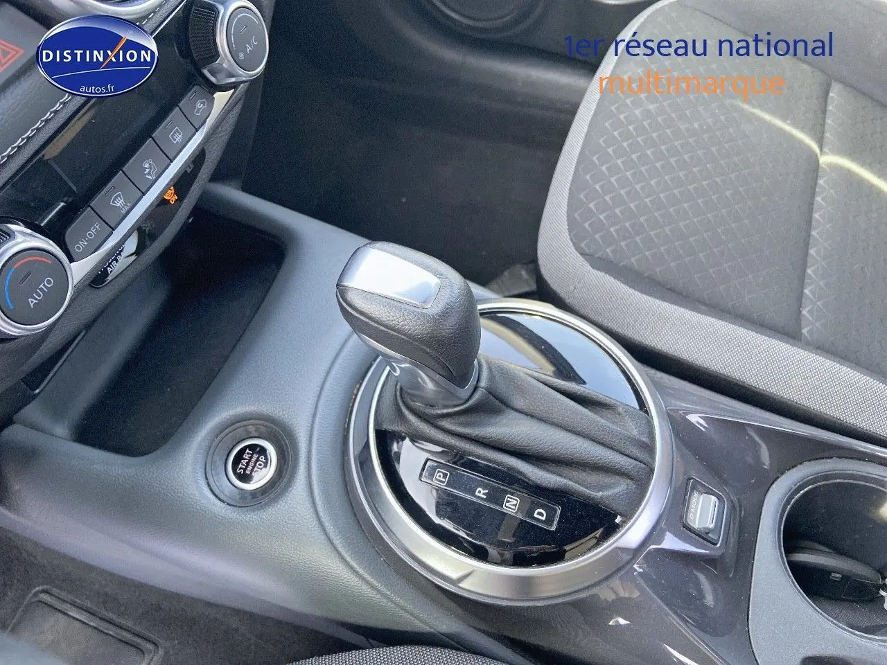 Le levier de vitesses automatique et le bouton start/stop du Nissan Juke gris clair vus de dessus côté console centrale.