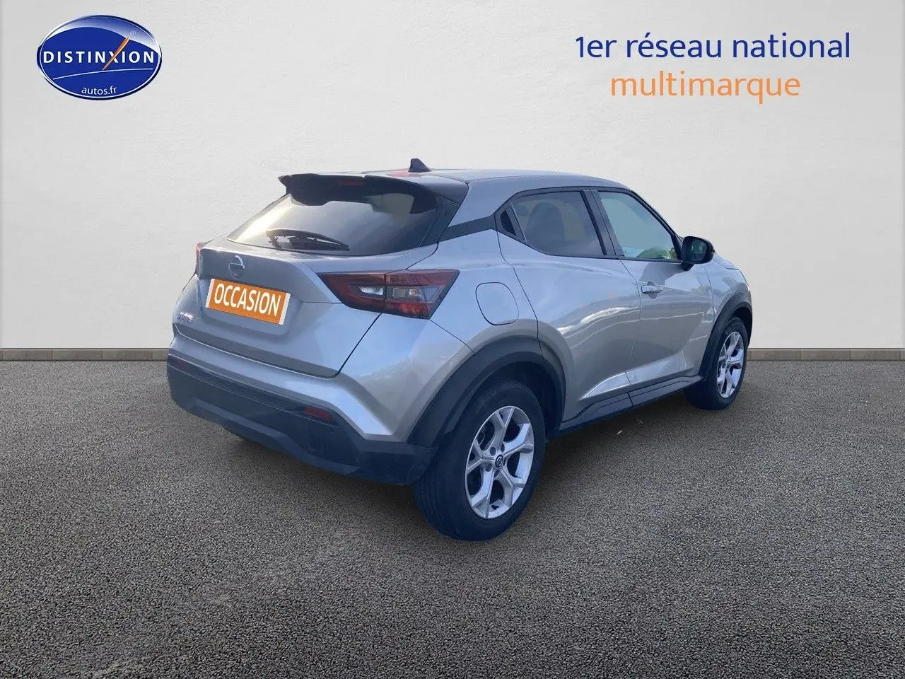 Nissan Juke gris clair vu de 3/4 arrière droit, avec jantes alliage et toit noir contrasté.