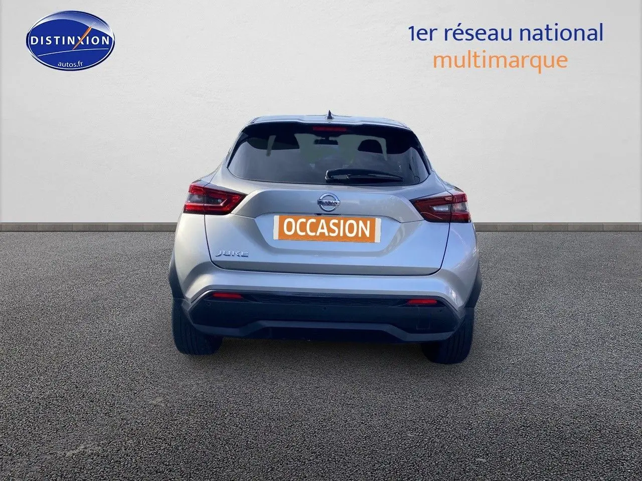 Vue arrière d'un Nissan Juke gris clair 2021 avec feux LED et logo Nissan bien visibles sur fond neutre.