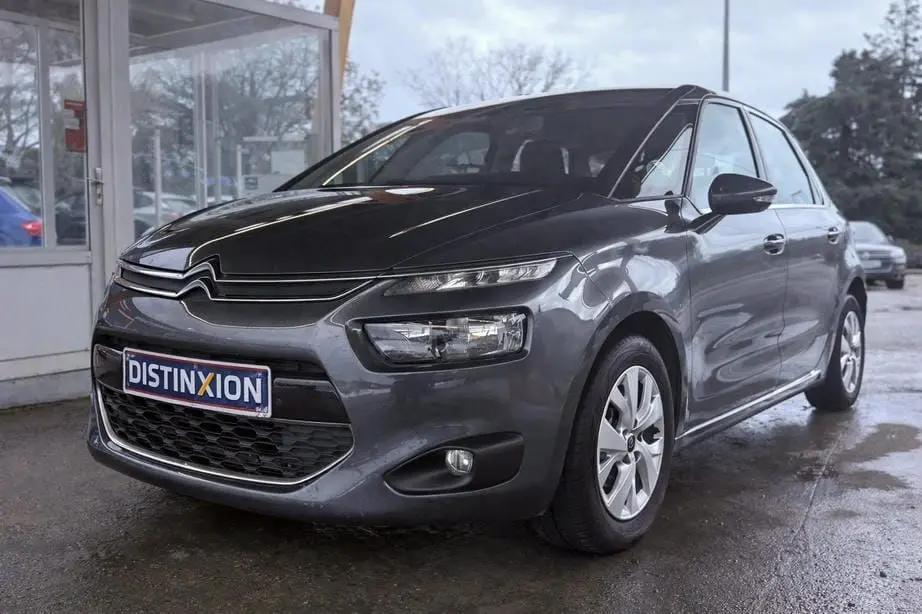 Vue 3/4 avant droit d'une Citroën C4 Picasso gris platinium métallisé avec calandre distinctive et feux LED fins.