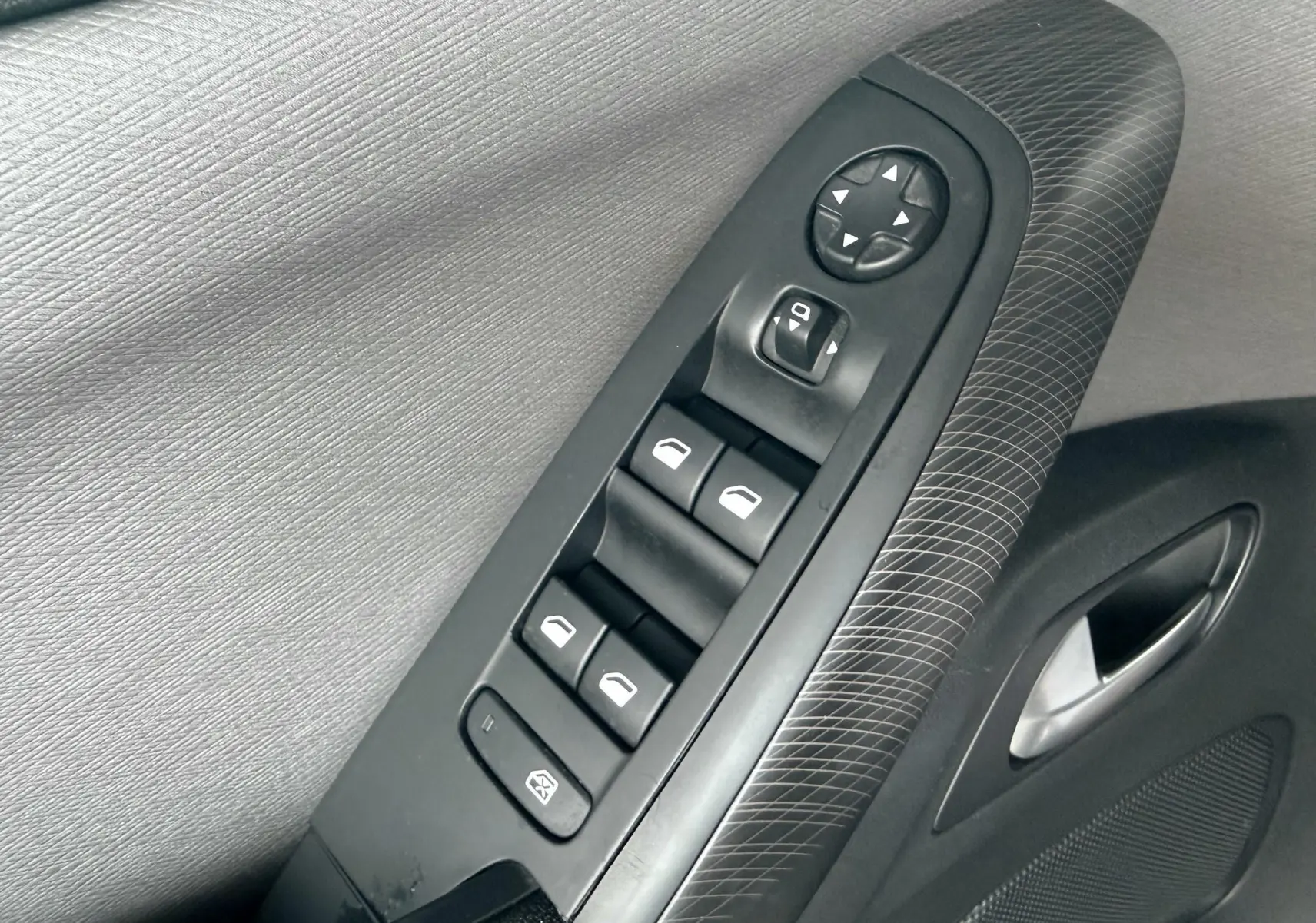 Gros plan sur la commande des vitres électriques et rétroviseurs côté conducteur de la Citroën C4 Picasso gris platinium.