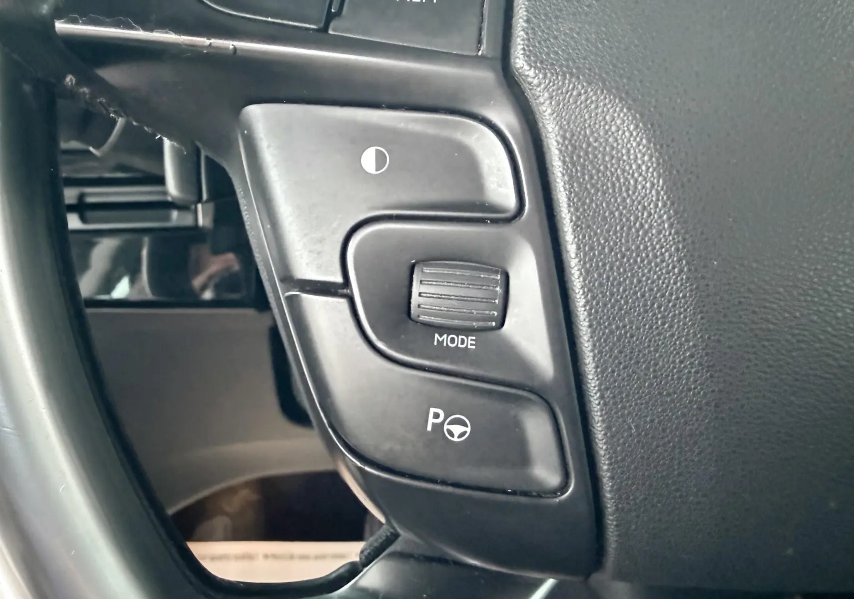 Gros plan sur les commandes au volant noir de la Citroën C4 Picasso gris platinium, côté gauche du volant.