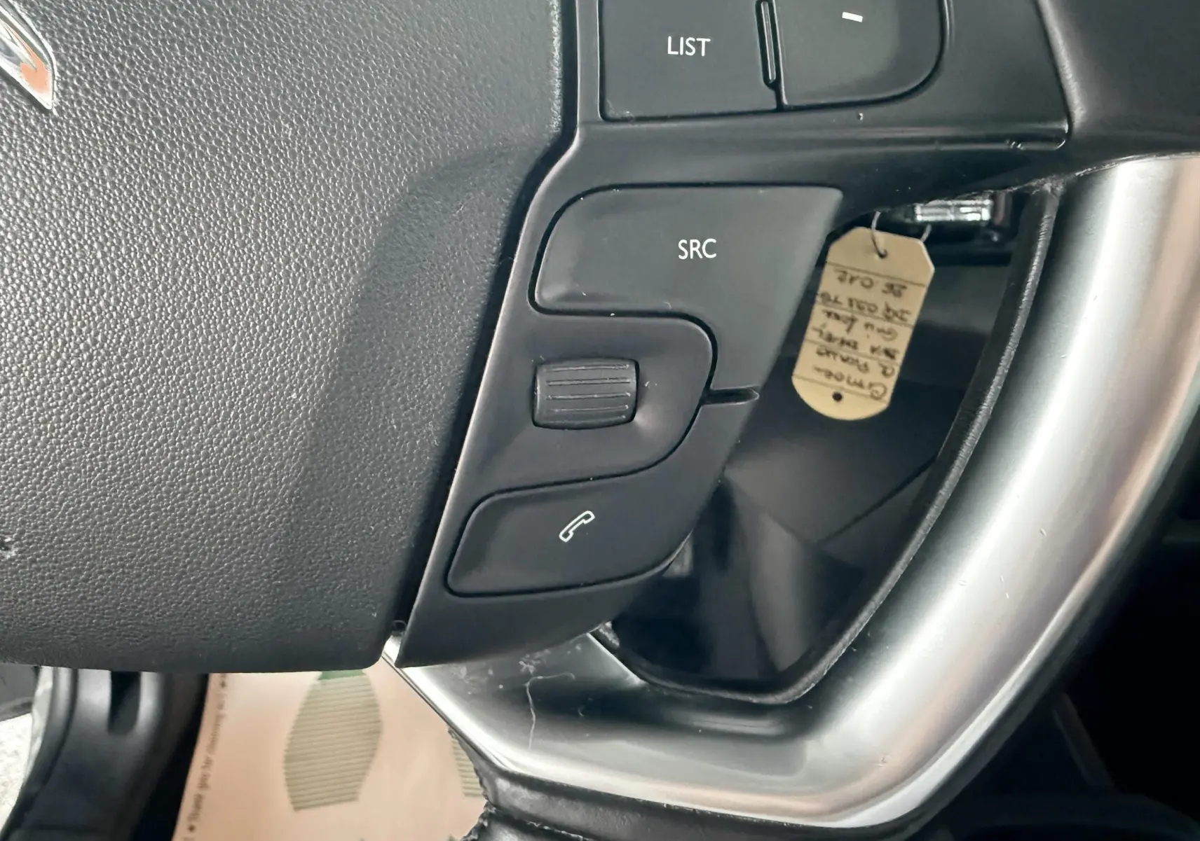 Gros plan sur les commandes au volant gris et noir de la Citroën C4 Picasso 2015, côté gauche.