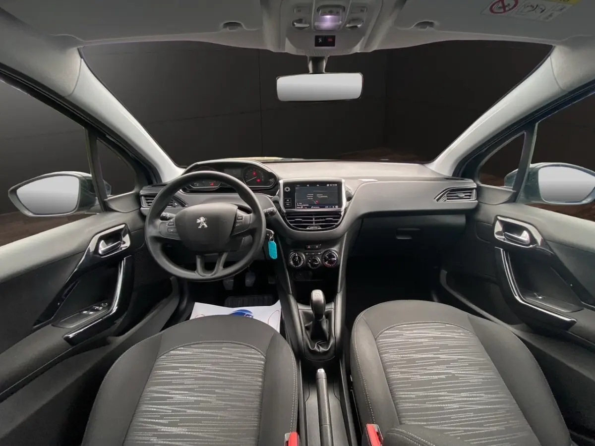 Vue intérieure frontale du poste de conduite de la Peugeot 208 Affaire noire avec tableau de bord tactile et volant multifonctions.