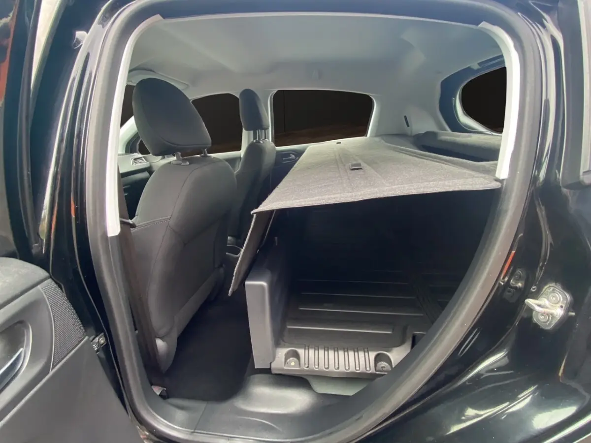 Vue intérieure côté gauche de la Peugeot 208 Affaire noire, montrant les sièges avant et l'espace de chargement avec cloison.