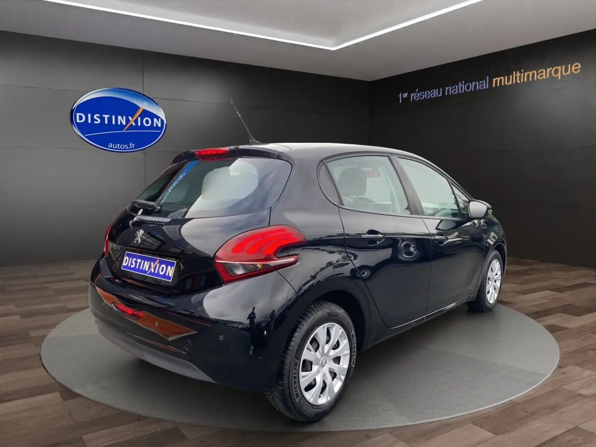 Vue 3/4 arrière droite d'une Peugeot 208 AFFAIRE BlueHDi 100 noire, avec feux arrière distinctifs et jantes argentées.