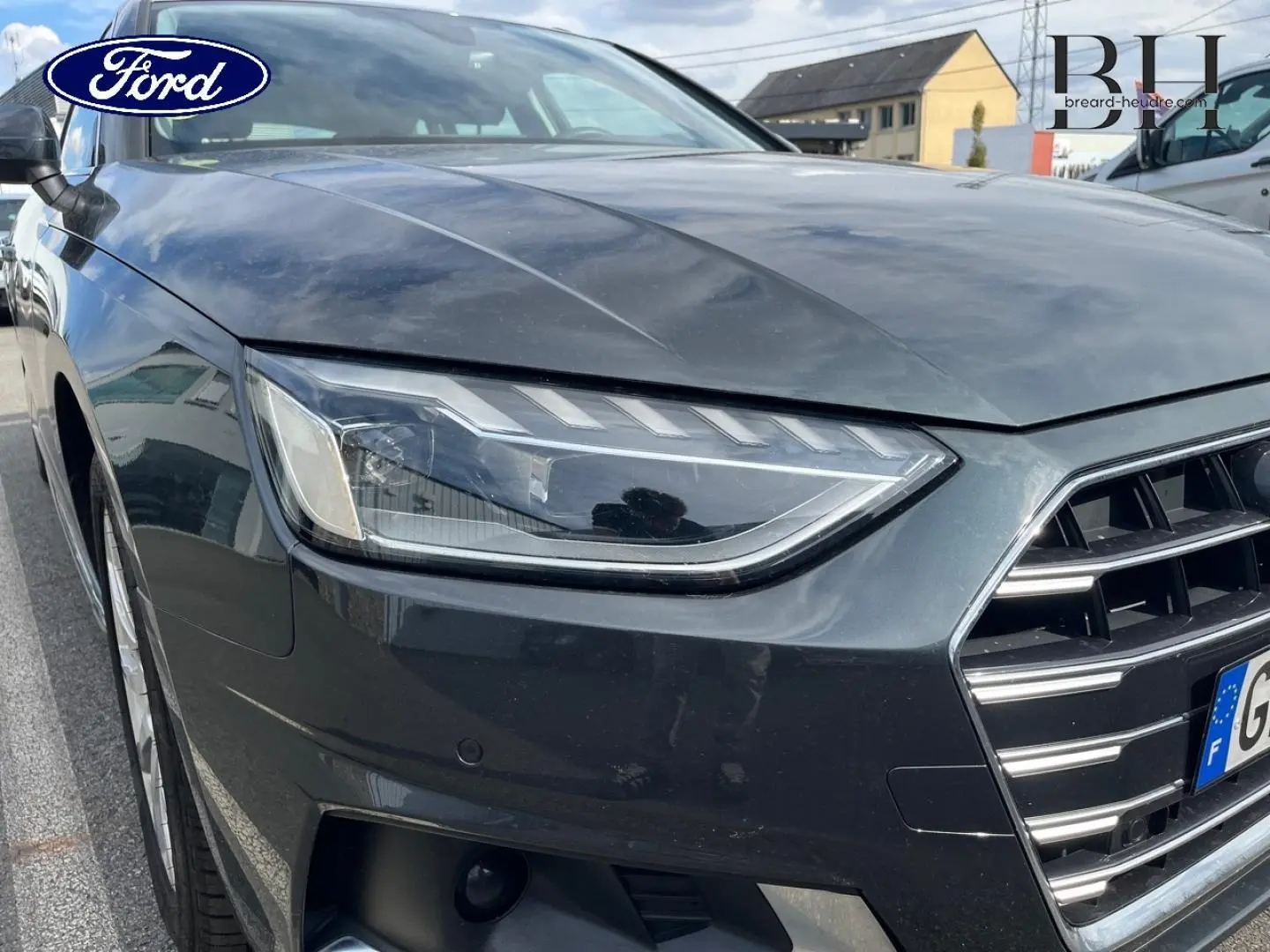 Gros plan sur l'avant droit de l'Audi A4 Avant gris Manhattan métallisé, mettant en valeur le phare LED et la calandre distinctive.