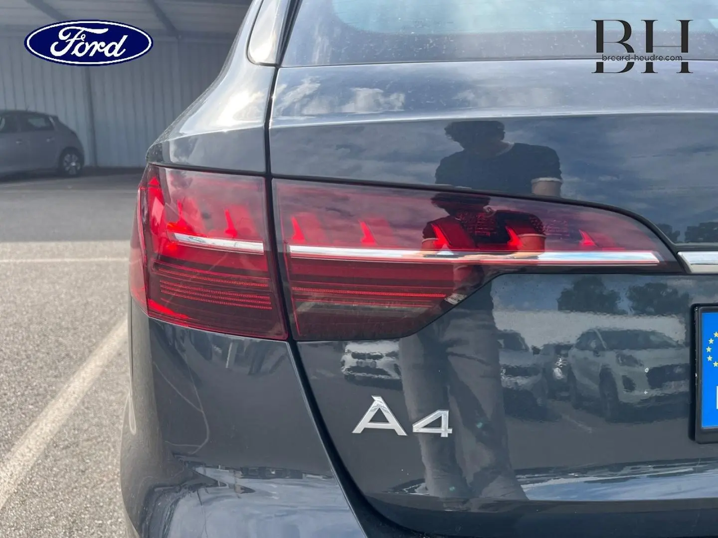 Gros plan sur l'arrière gauche d'une Audi A4 Avant gris Manhattan métallisé avec feux arrière LED et logo A4 visible.