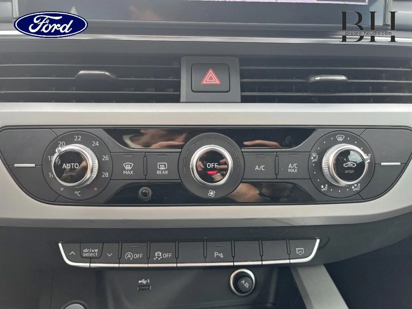 Tableau de bord gris avec commandes climatisation et boutons multifonctions, vue frontale intérieure d'une Audi A4 Avant 2022.
