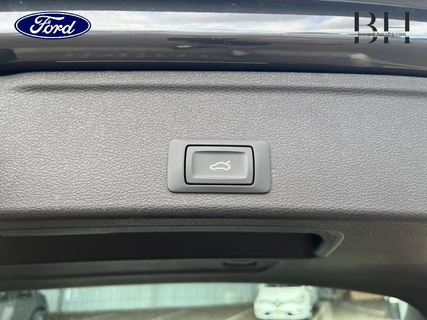 Bouton d'ouverture électrique du coffre sur la partie intérieure du hayon d'une Audi A4 Avant gris Manhattan métallisé.