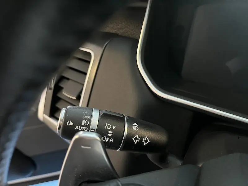 Gros plan sur la manette de clignotants et feux du Range Rover Sport blanc, intérieur noir, côté gauche du volant.