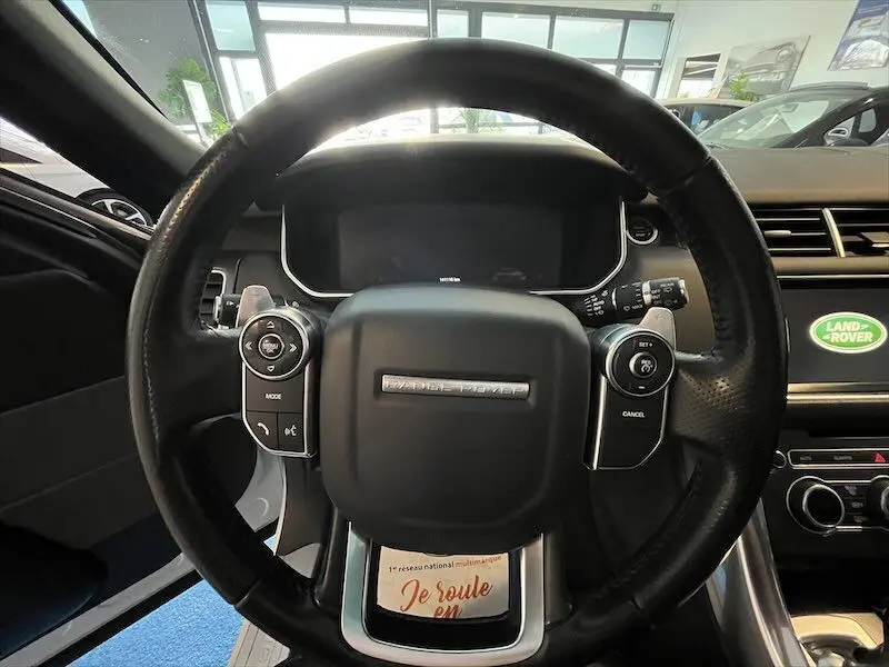 Vue centrée sur le volant noir du Range Rover Sport 2018 avec tableau de bord et écran Land Rover en arrière-plan.