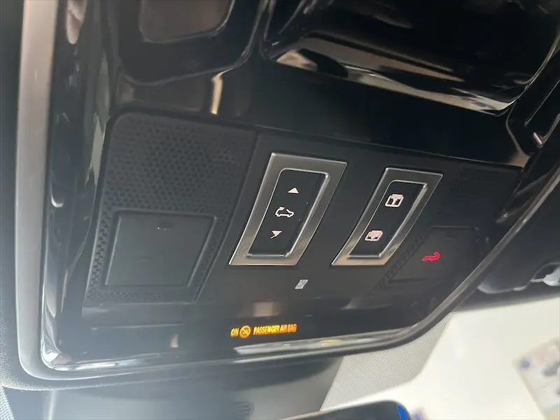 Vue rapprochée du plafonnier noir du Range Rover Sport blanc, avec commandes d'ouverture et témoin airbag passager.