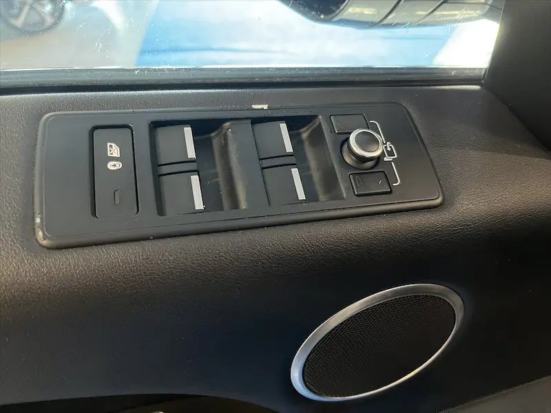 Panneau de commandes des vitres et rétroviseurs côté conducteur du Range Rover Sport blanc, avec haut-parleur intégré.