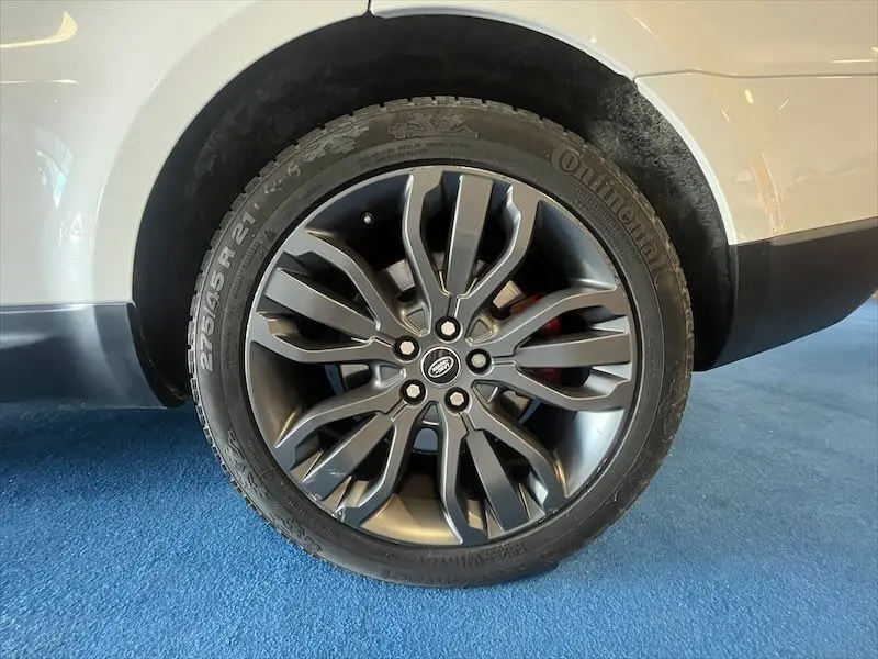 Gros plan sur la roue arrière droite du Range Rover Sport blanc, mettant en valeur la jante noire au design moderne.