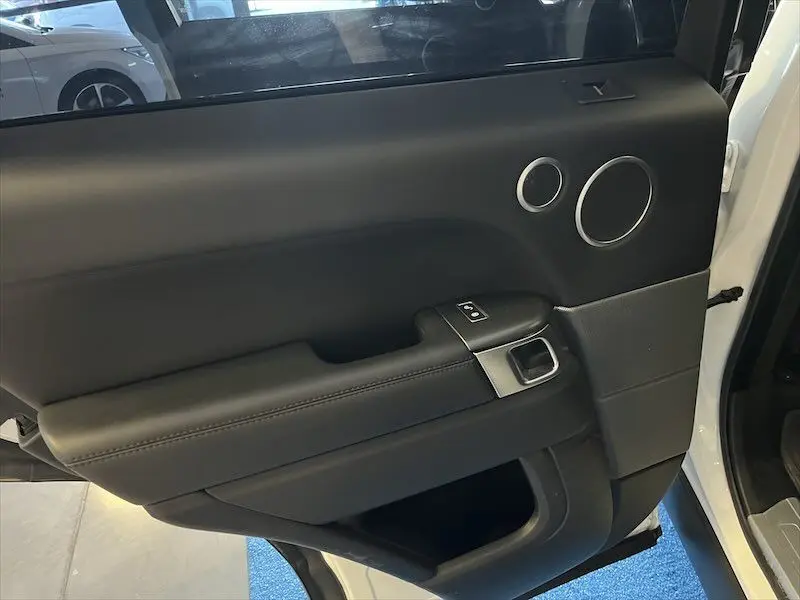 Gros plan sur la porte intérieure côté gauche en cuir noir du Range Rover Sport blanc 2018, avec commandes de fenêtre.