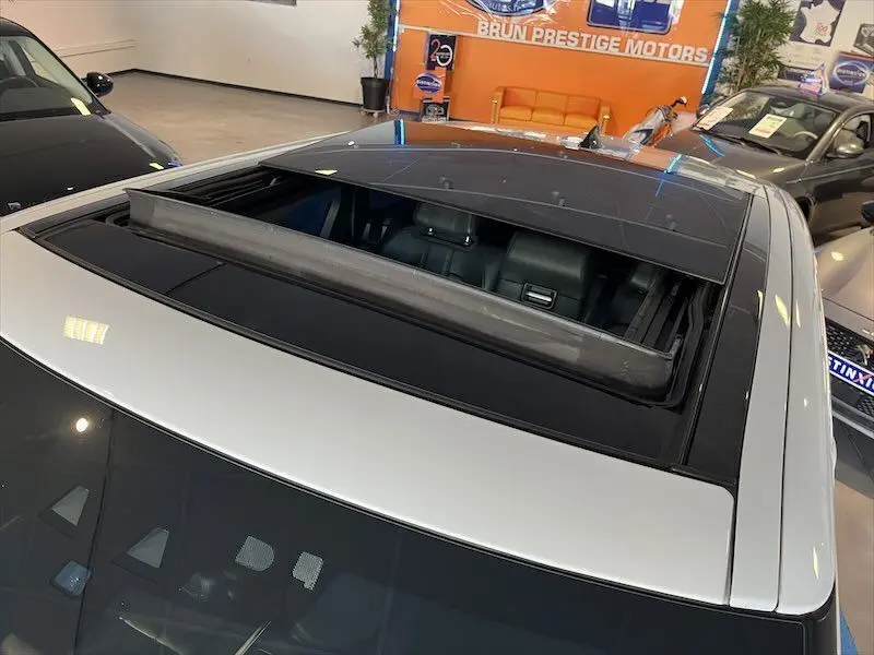 Toit ouvrant panoramique ouvert sur un Range Rover Sport blanc vu du dessus dans un showroom.