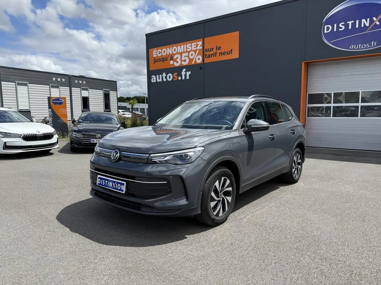Volkswagen Tiguan 1.5 eHybrid gris dauphin vu en 3/4 avant sur parking devant concession Distinxion.