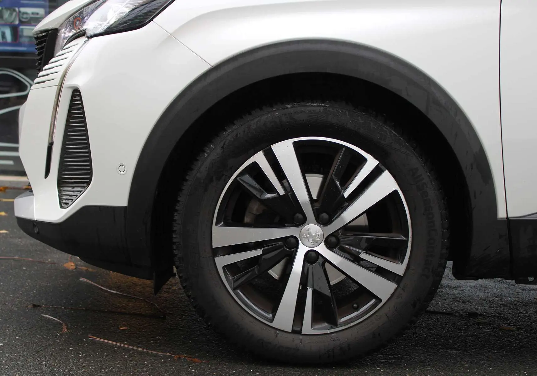 Gros plan sur la roue avant gauche du Peugeot 3008 blanc nacré, soulignant la jante alliage bicolore moderne.