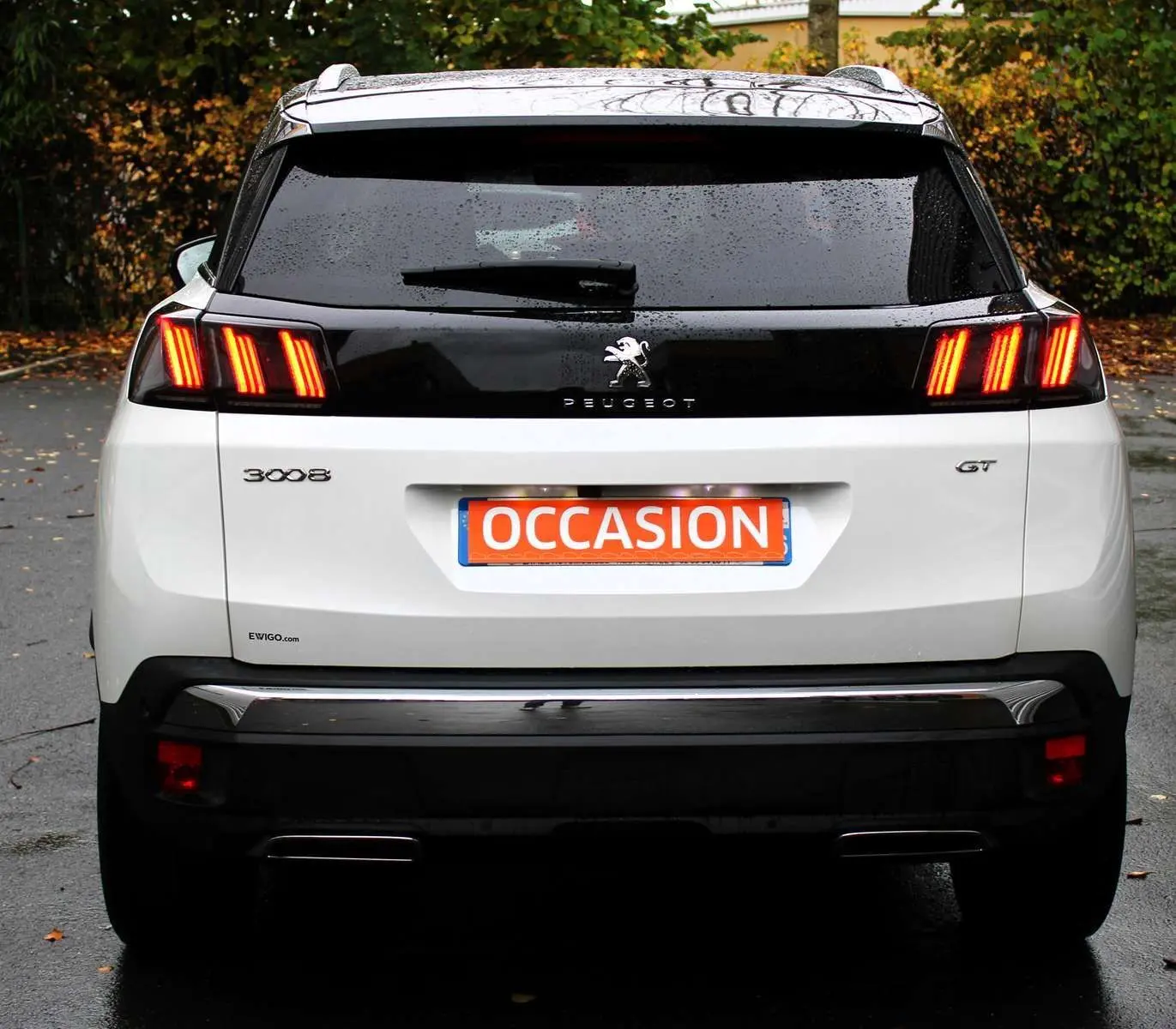 Vue arrière d'un Peugeot 3008 blanc nacré avec feux allumés et toit panoramique ouvrant visible.