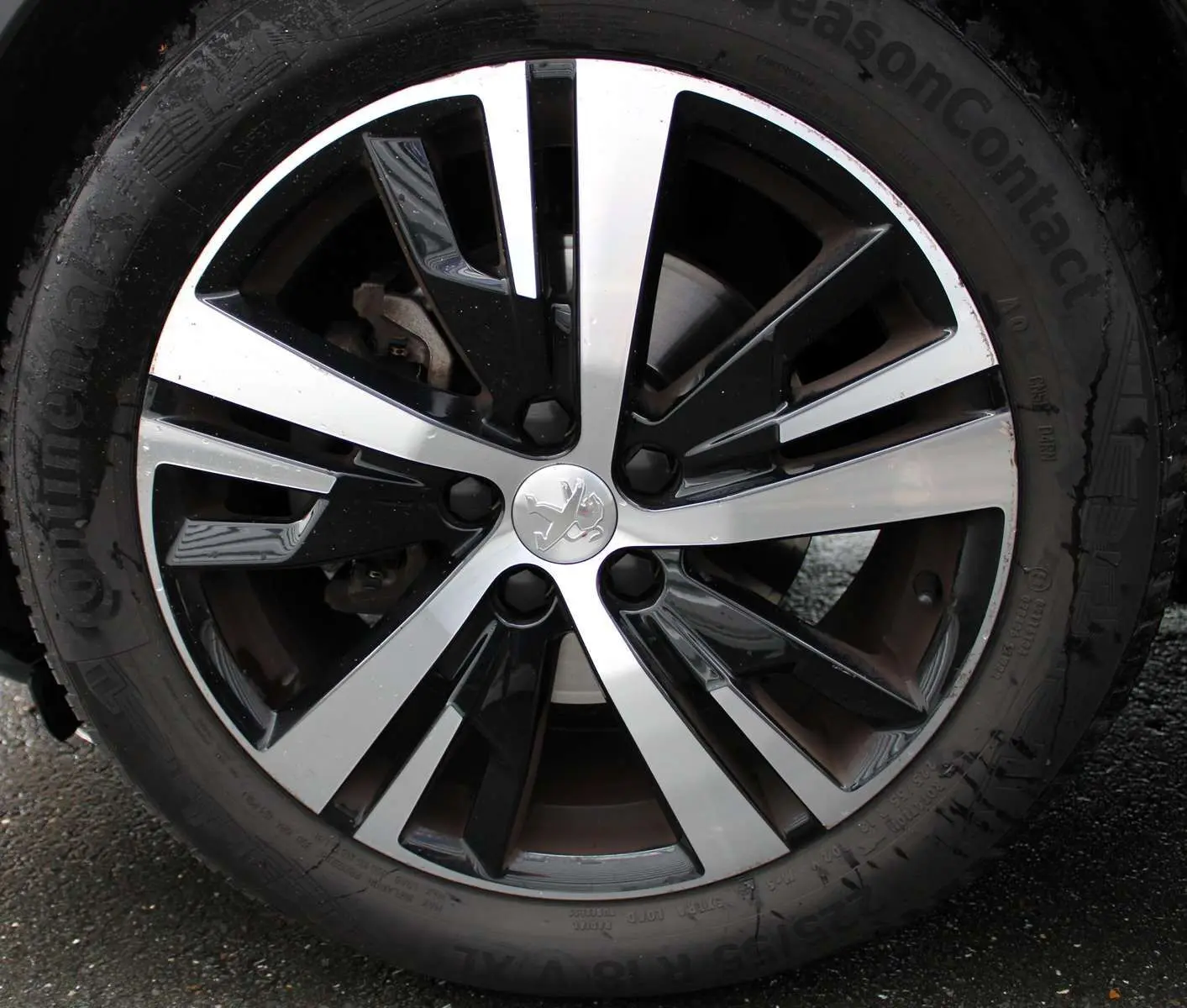 Gros plan sur la jante alliage bicolore noire et argentée avec logo lion Peugeot du 3008 blanc nacré 2025.