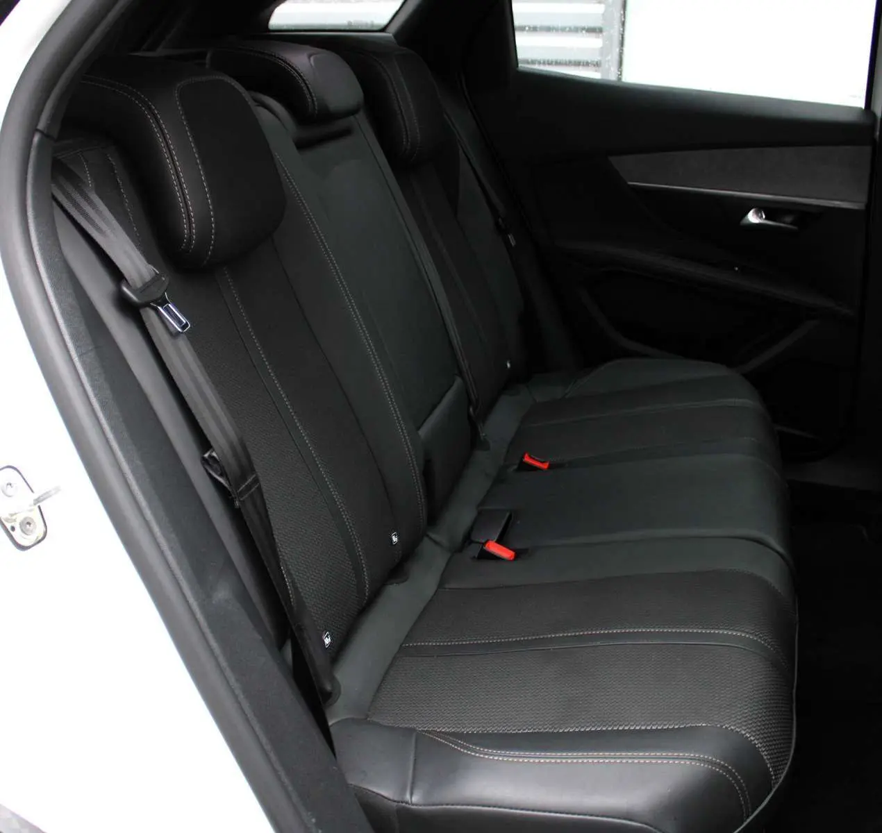 Vue intérieure côté gauche montrant la banquette arrière en cuir noir du Peugeot 3008 GT blanc nacré 2025 avec finitions soignées.