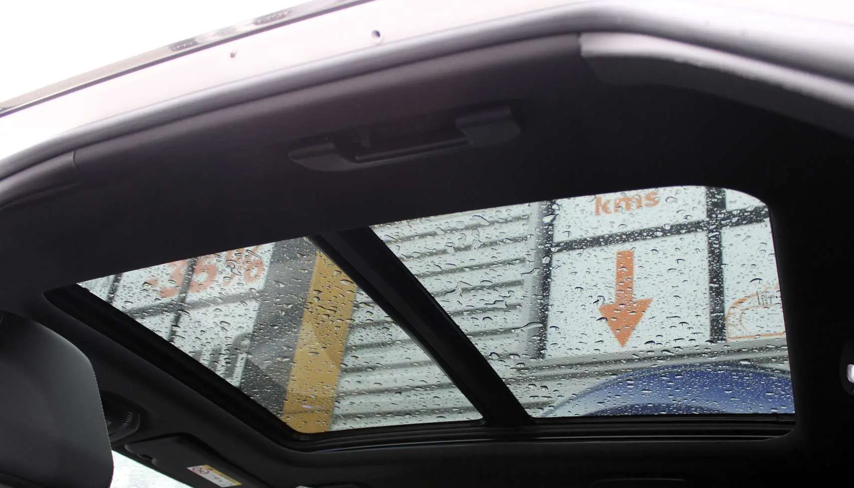 Toit panoramique ouvrant avec gouttes de pluie visible depuis l'intérieur d'un Peugeot 3008 blanc nacré 2025.