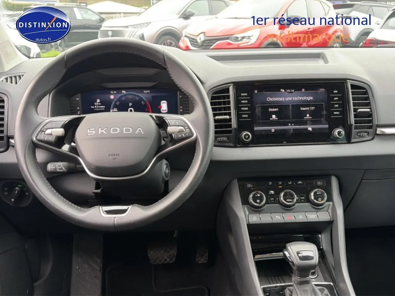 Vue intérieure centrée sur le volant cuir SKODA et l'écran tactile du tableau de bord du Karoq noir 2025.