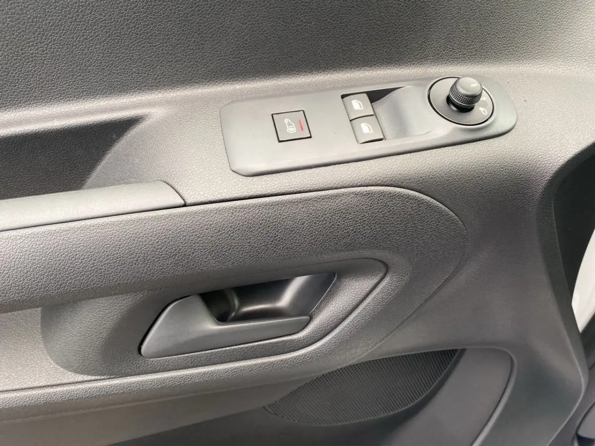 Gros plan sur la porte intérieure côté conducteur du Peugeot Partner blanc, avec commandes de vitres et rétroviseurs.