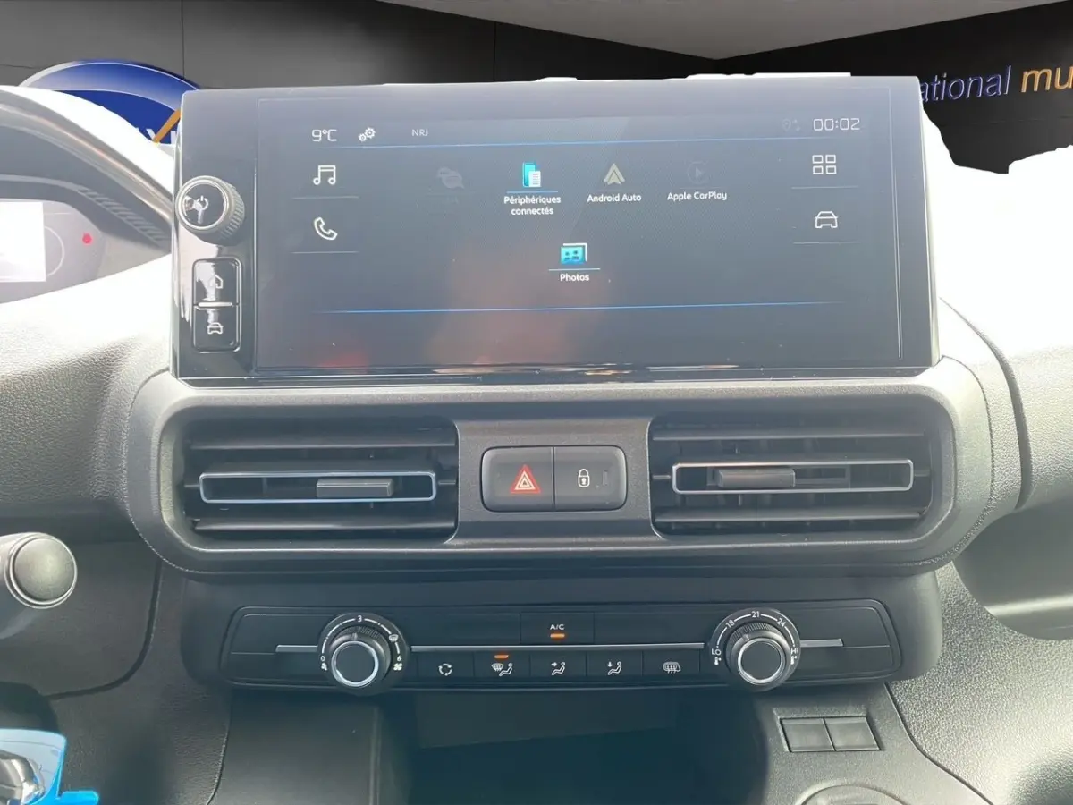 Vue rapprochée du tableau de bord du Peugeot Partner 2024 avec écran tactile central et commandes de climatisation.