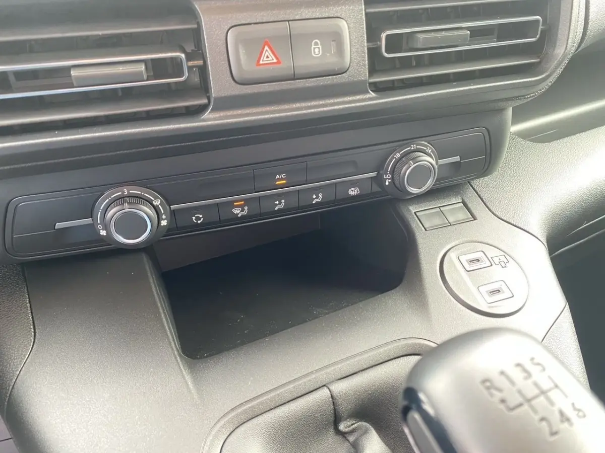 Vue rapprochée de la console centrale noire du Peugeot Partner 2024 avec commandes climatisation et levier de vitesses manuel.