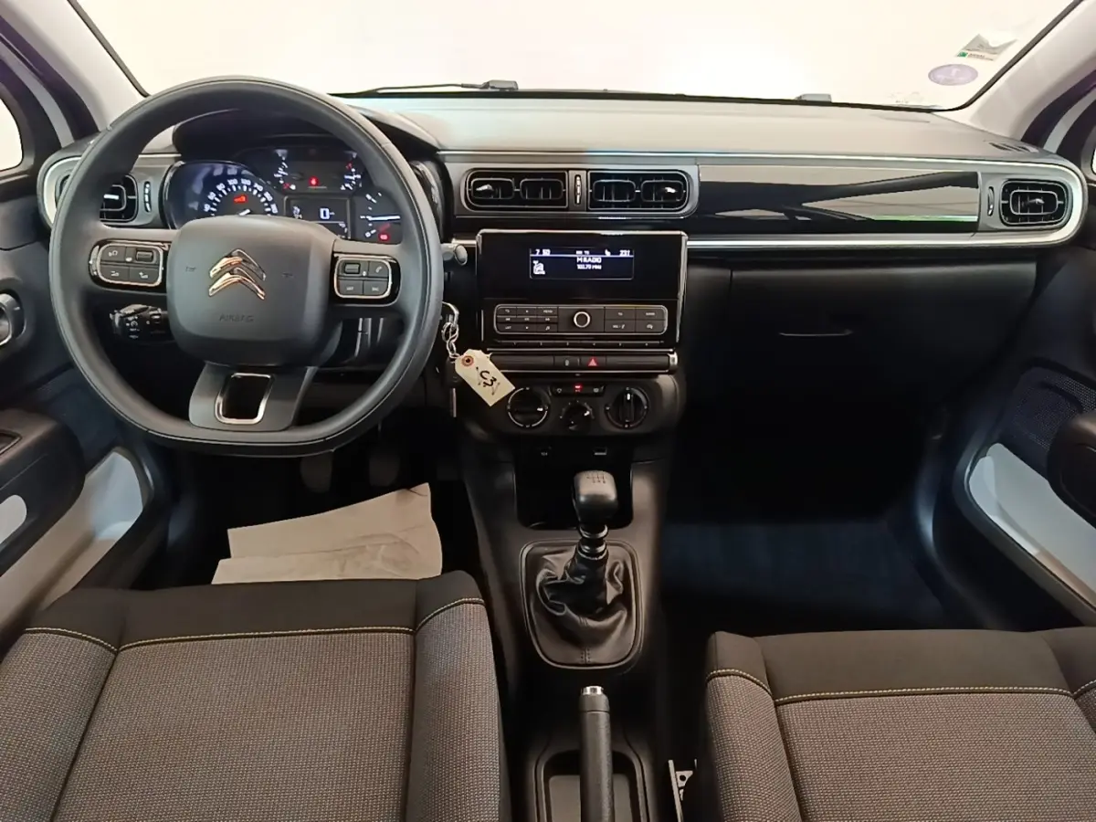 Vue intérieure avant de la Citroën C3 blanche de 2019, montrant le tableau de bord et la boîte manuelle.