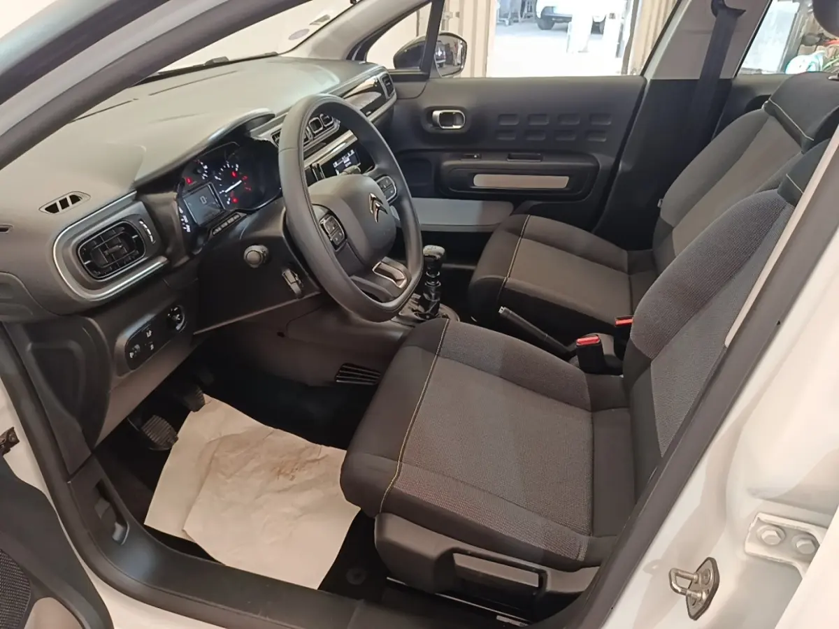 Intérieur de la Citroën C3 blanc, vue côté conducteur, montrant sièges gris et tableau de bord moderne.