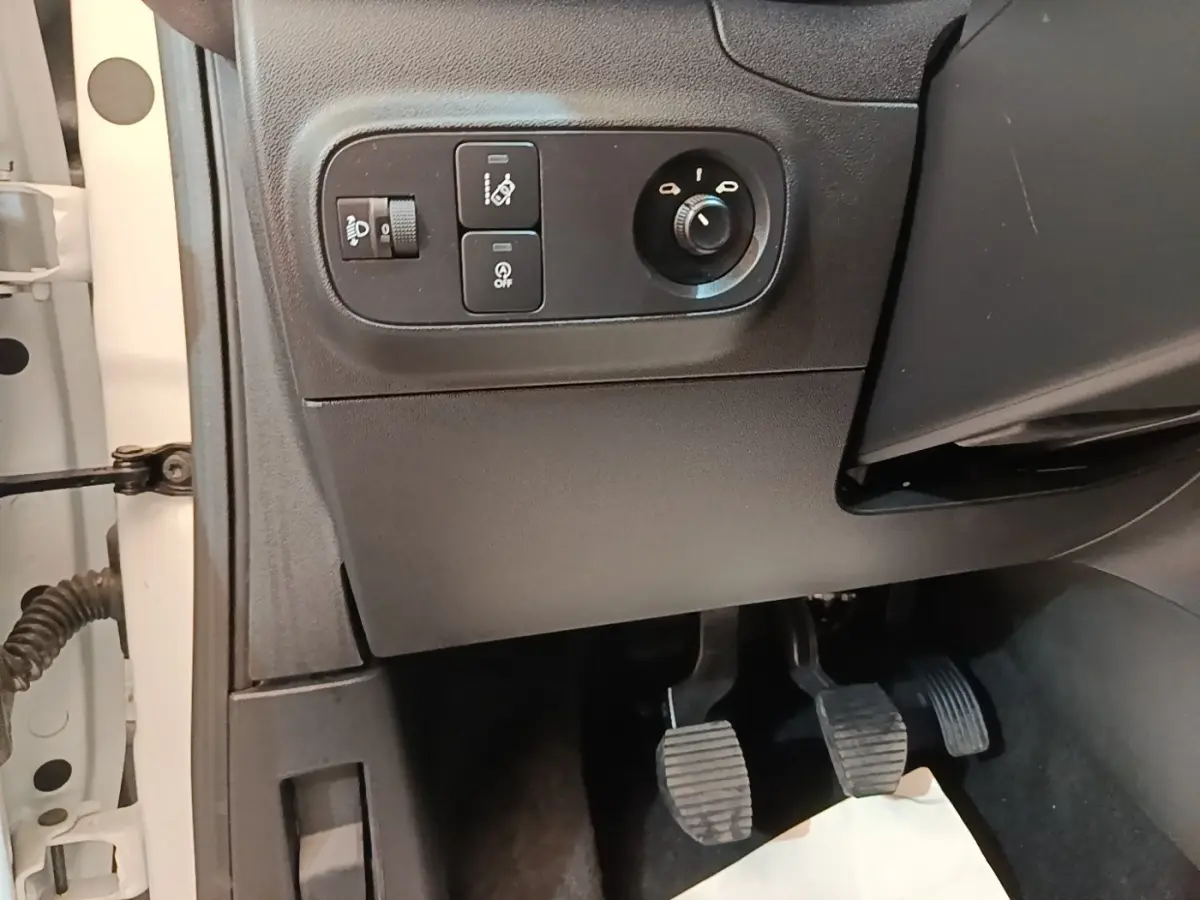 Vue intérieure côté conducteur montrant les commandes d'éclairage et les pédales d'une Citroën C3 blanche de 2019.