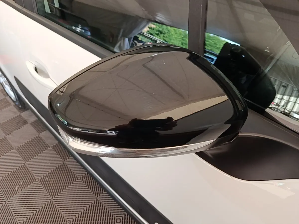 Gros plan sur le rétroviseur noir brillant côté gauche d'une Citroën C3 blanche vue de profil.