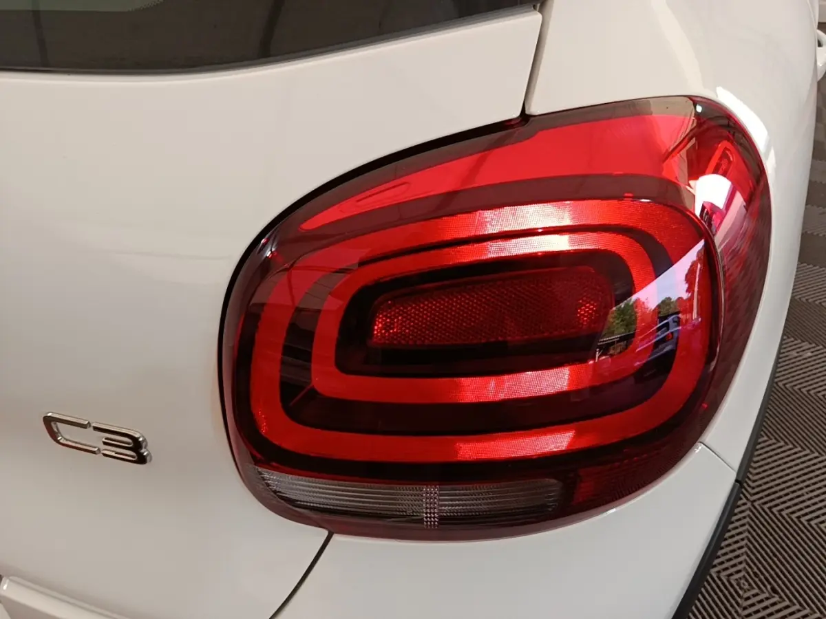 Gros plan sur le feu arrière droit rouge d'une Citroën C3 blanche, modèle 2019, avec logo C3 visible.