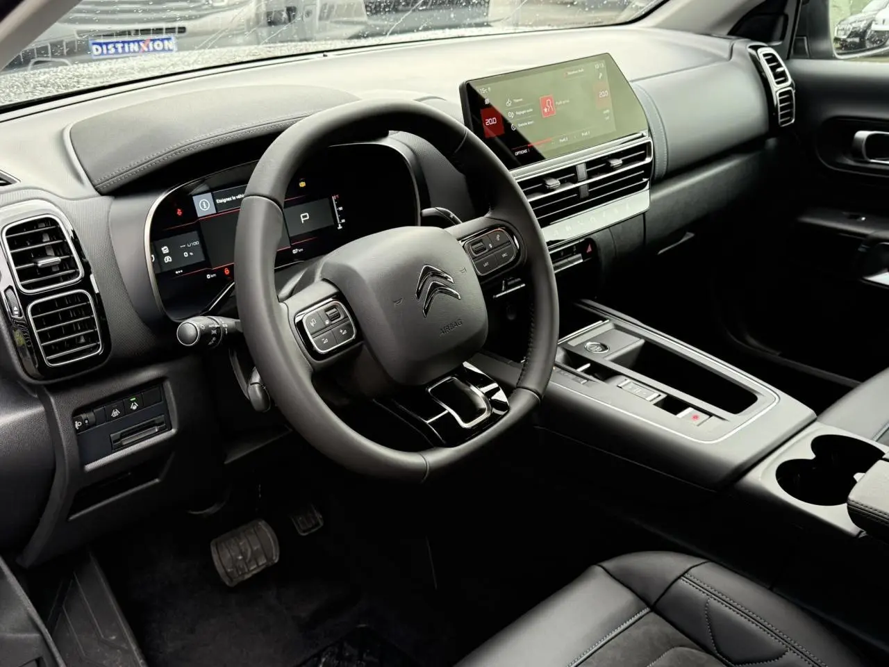 Intérieur avant droit du Citroën C5 Aircross Hybrid 2025 avec volant cuir, écran tactile 10 pouces et finition Urban Black.