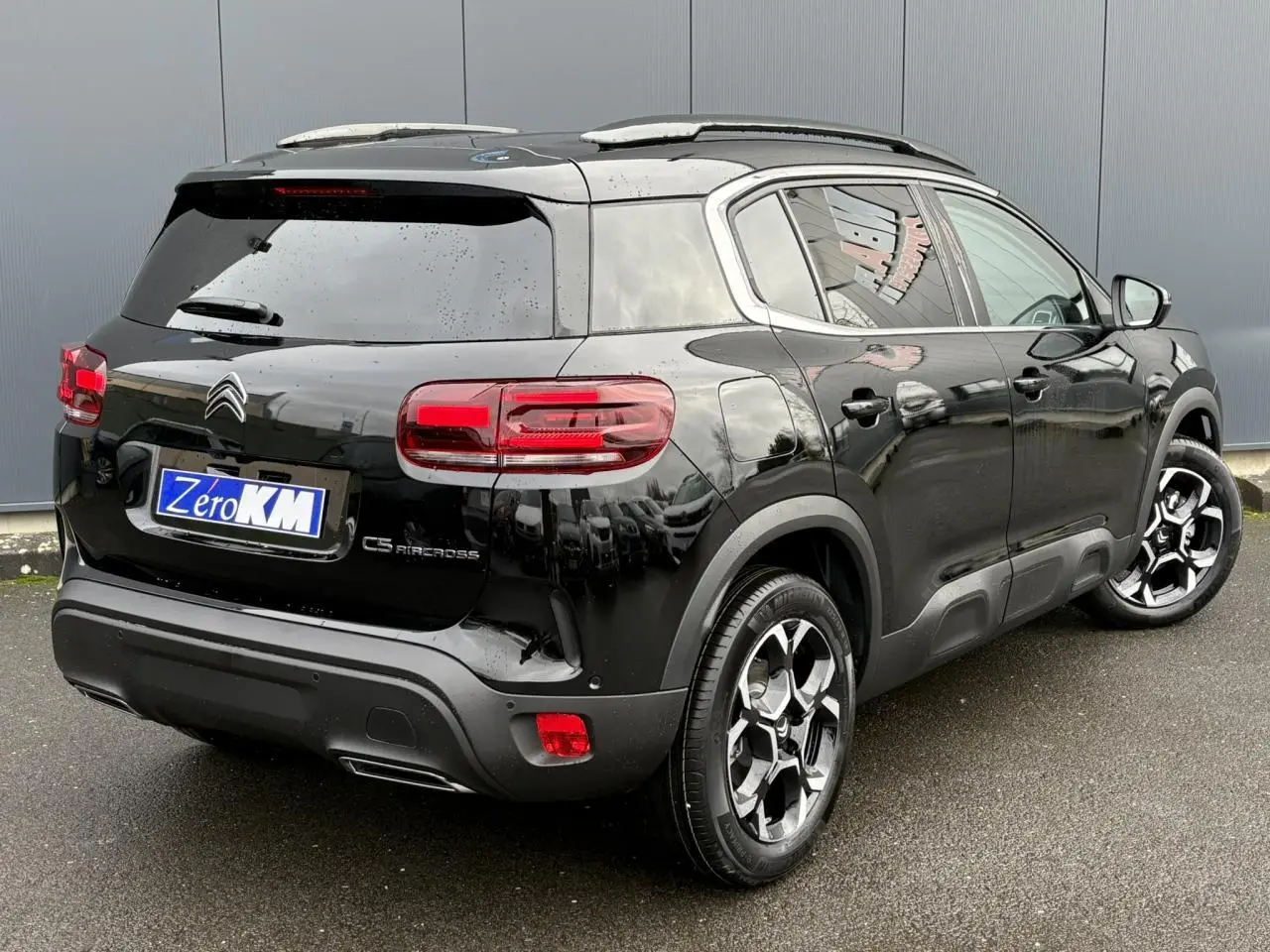 Vue 3/4 arrière droit d'un Citroën C5 Aircross Hybrid noir Perla avec jantes alliage bi-ton et vitres surteintées.