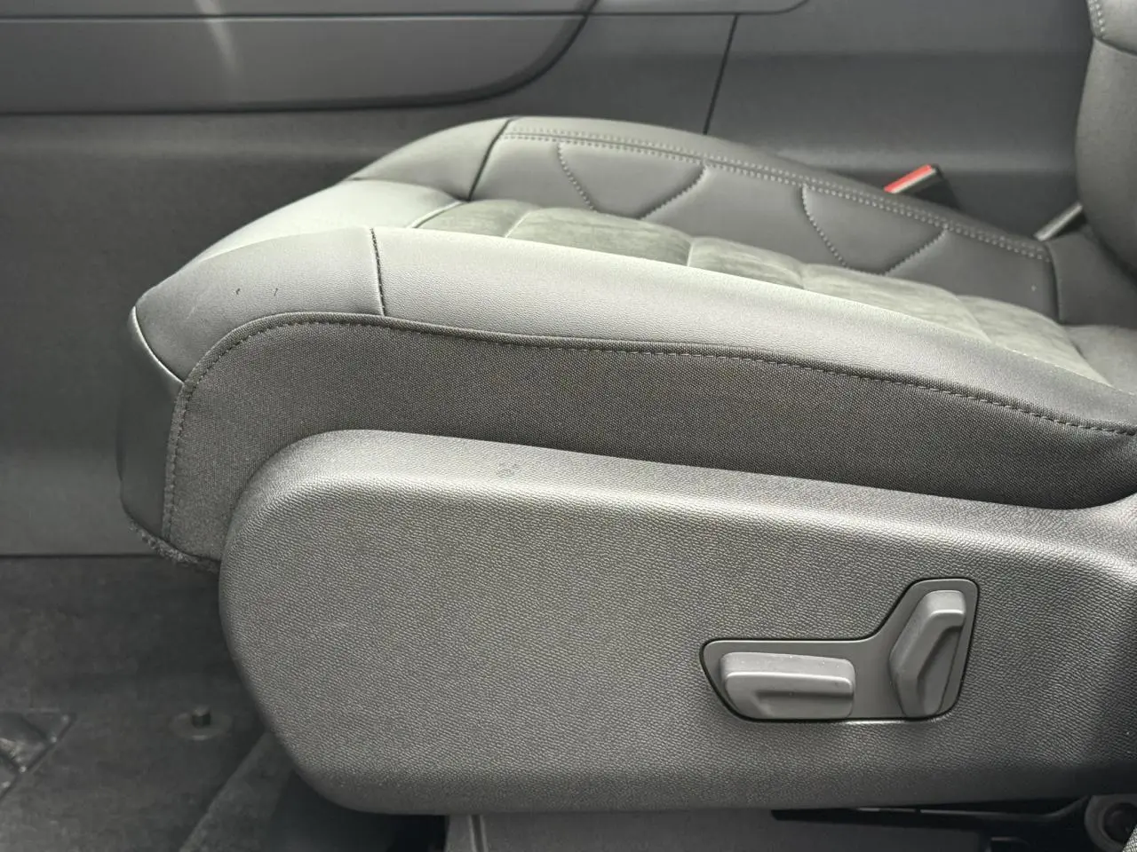 Gros plan sur le siège conducteur noir Alcantara et tissu effet cuir du Citroën C5 Aircross Hybrid 2025, avec commandes électriques visibles.