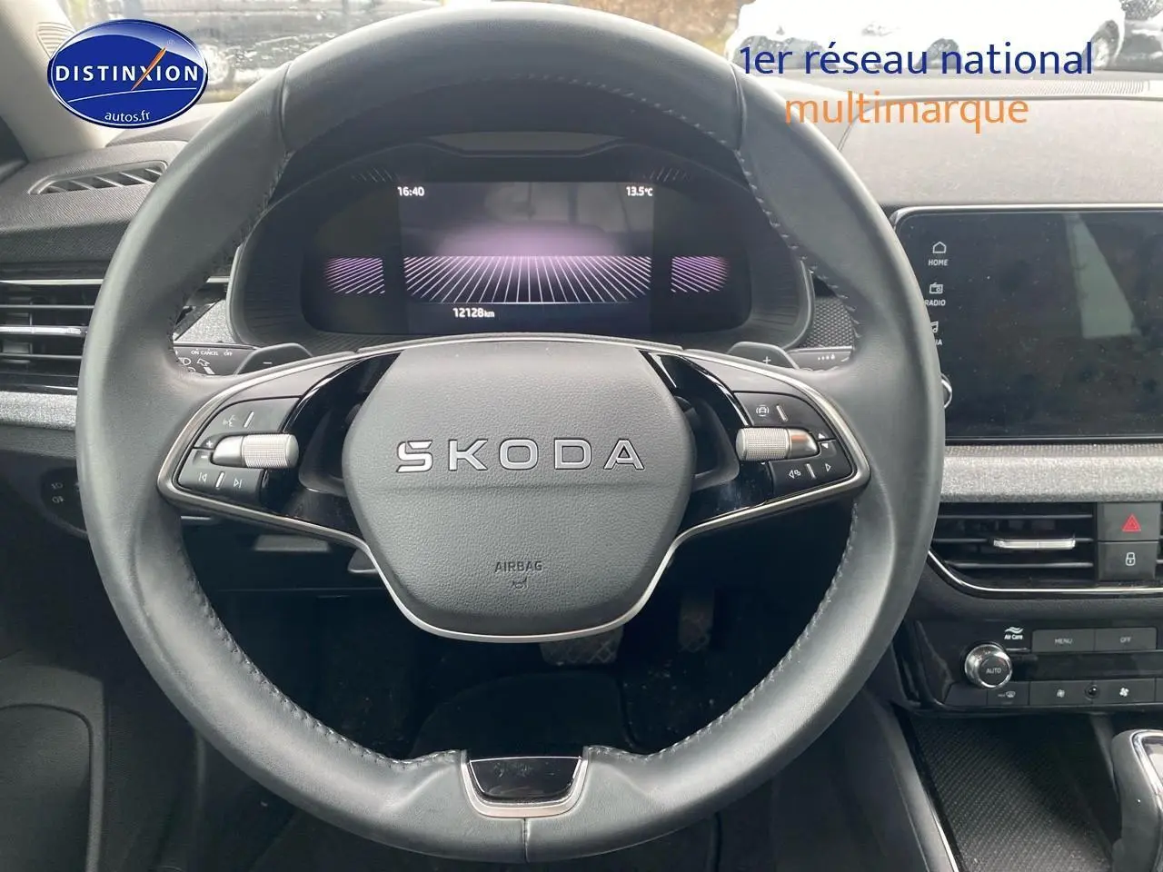 Vue rapprochée du volant cuir multifonction SKODA avec tableau de bord numérique et écran tactile central.